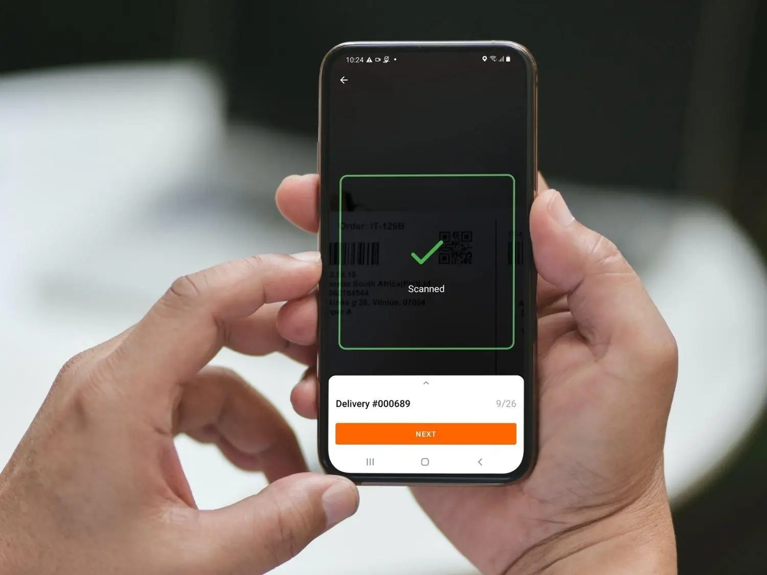 Driver app check-in / check-out — smartphone showing scanned delivery confirmation and NEXT button for stop workflow